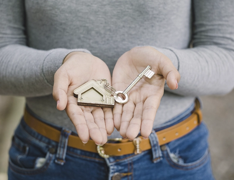 manos sujetando llave con llavero en forma de casa